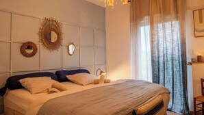 Quarto com cama, um candelabro, espelho e janela com cortinas.