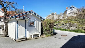 En liten vit byggnad med ett sluttande tak, en dörr och ett litet fönster.