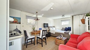 Ett kompakt bostadsutrymme med ett litet kök, en matplats, ett sovrum och en röd soffa.