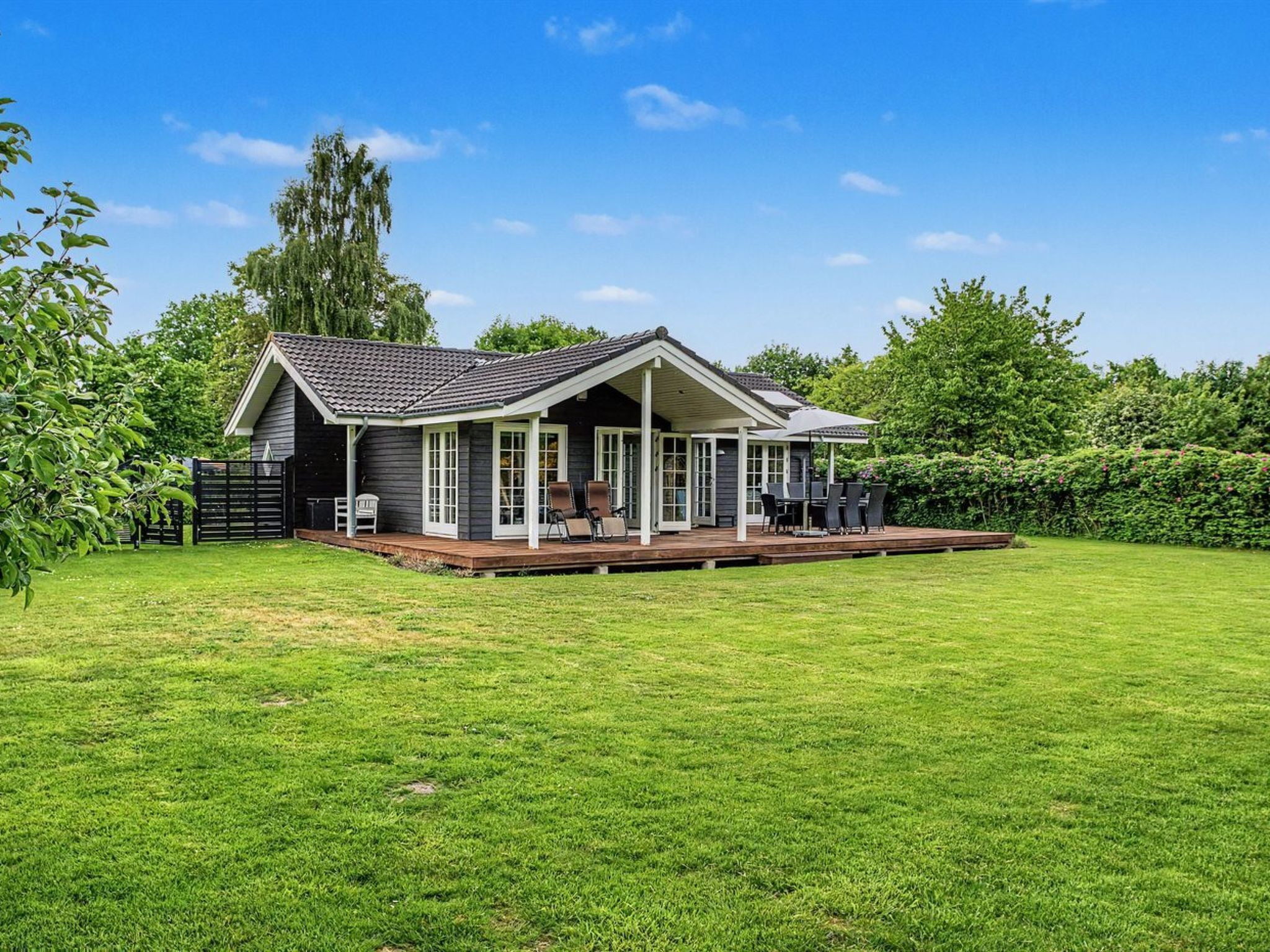Een huis met een overdekte veranda, een gazon en een omheining.