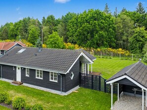 Ein Wohnhaus mit dunklem Dach, weißem Zierfachwerk und einer kleinen Veranda.
