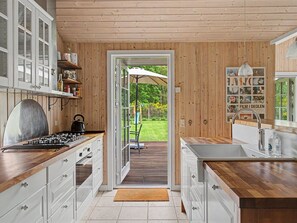 Eine moderne Küche mit Holzausstattung, einem Gaskochfeld und einem großen Fenster zum Garten.