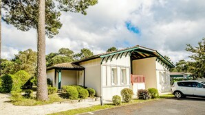 Una casa a un piano con un portico coperto, un'auto parcheggiata nel vialetto e un albero sul lato sinistro.
