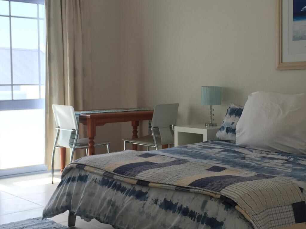 A bedroom with a bed, a desk, a chair, and a lamp.