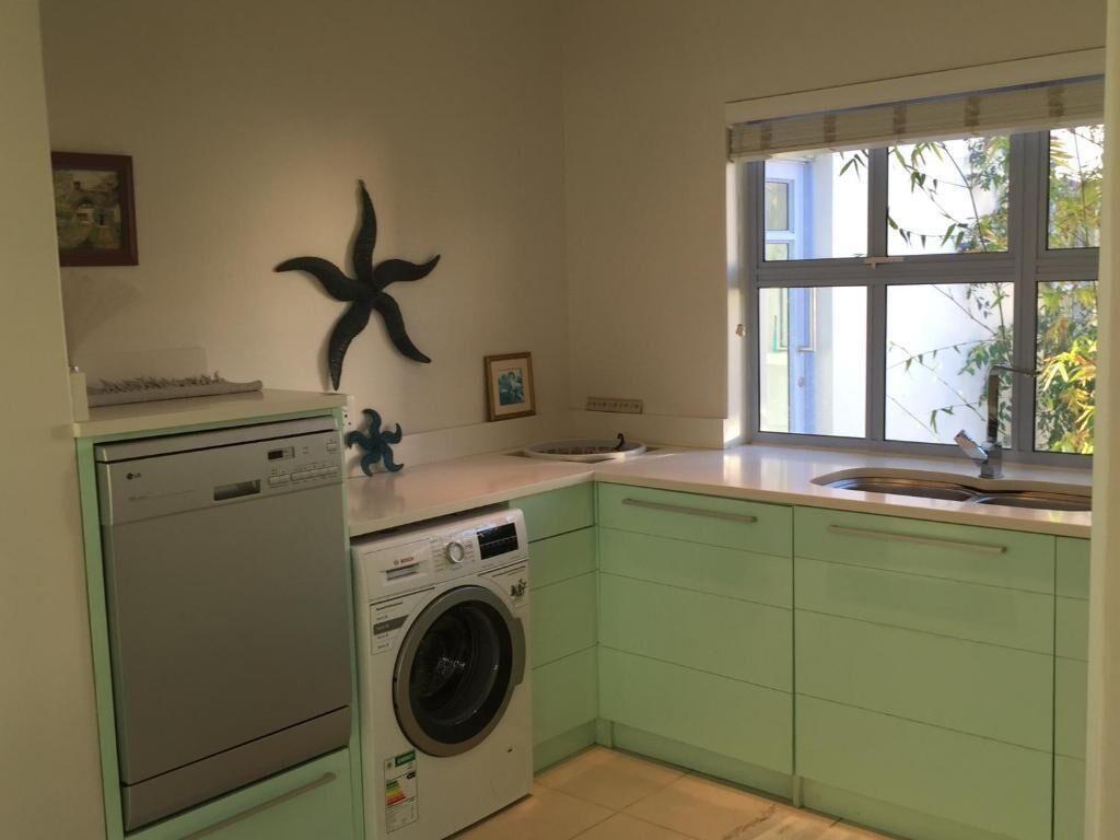 Une cuisine équipée d’un lave-linge, d’un évier, d’une fenêtre avec vue et d’une décoration murale représentant une étoile de mer.