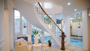 Un vaste espace de vie agrémenté d’un escalier en courbe, de grandes fenêtres et d’une vue sur une piscine.