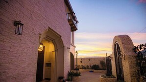 Un bâtiment en briques avec une entrée en arc de cercle, un portail en pierre et une vue sur le coucher du soleil.