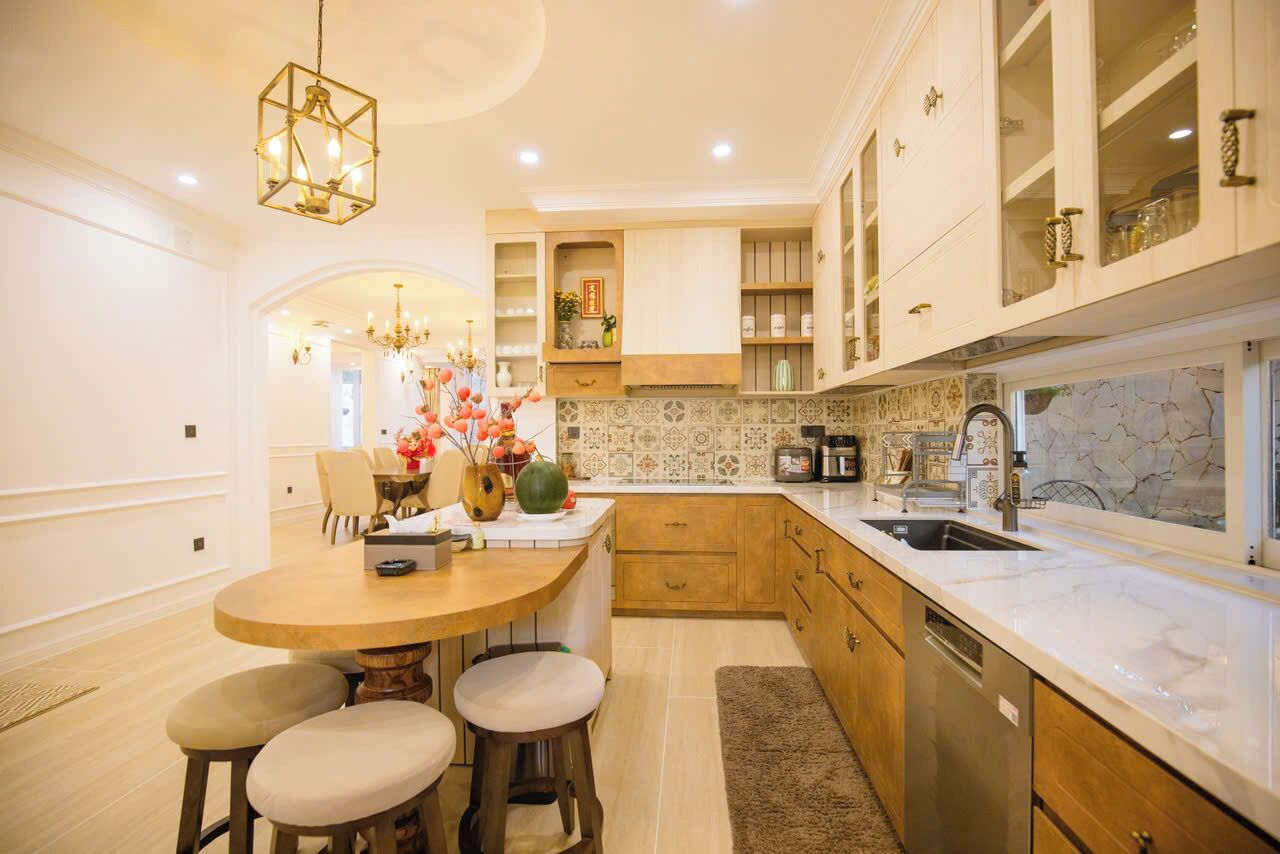 A modern kitchen with a round island, wooden cabinets, and a marble backsplash.