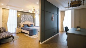 Une chambre d’hôtel moderne équipée d’un lit, de tables de chevet, d’un bureau et d’un lustre.