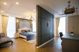 Quarto de hotel moderno com cama, mesas de cabeceira, escrivaninha e lustre.