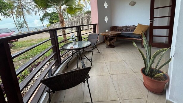 Un balcon avec une table, des chaises, un canapé et une plante en pot.