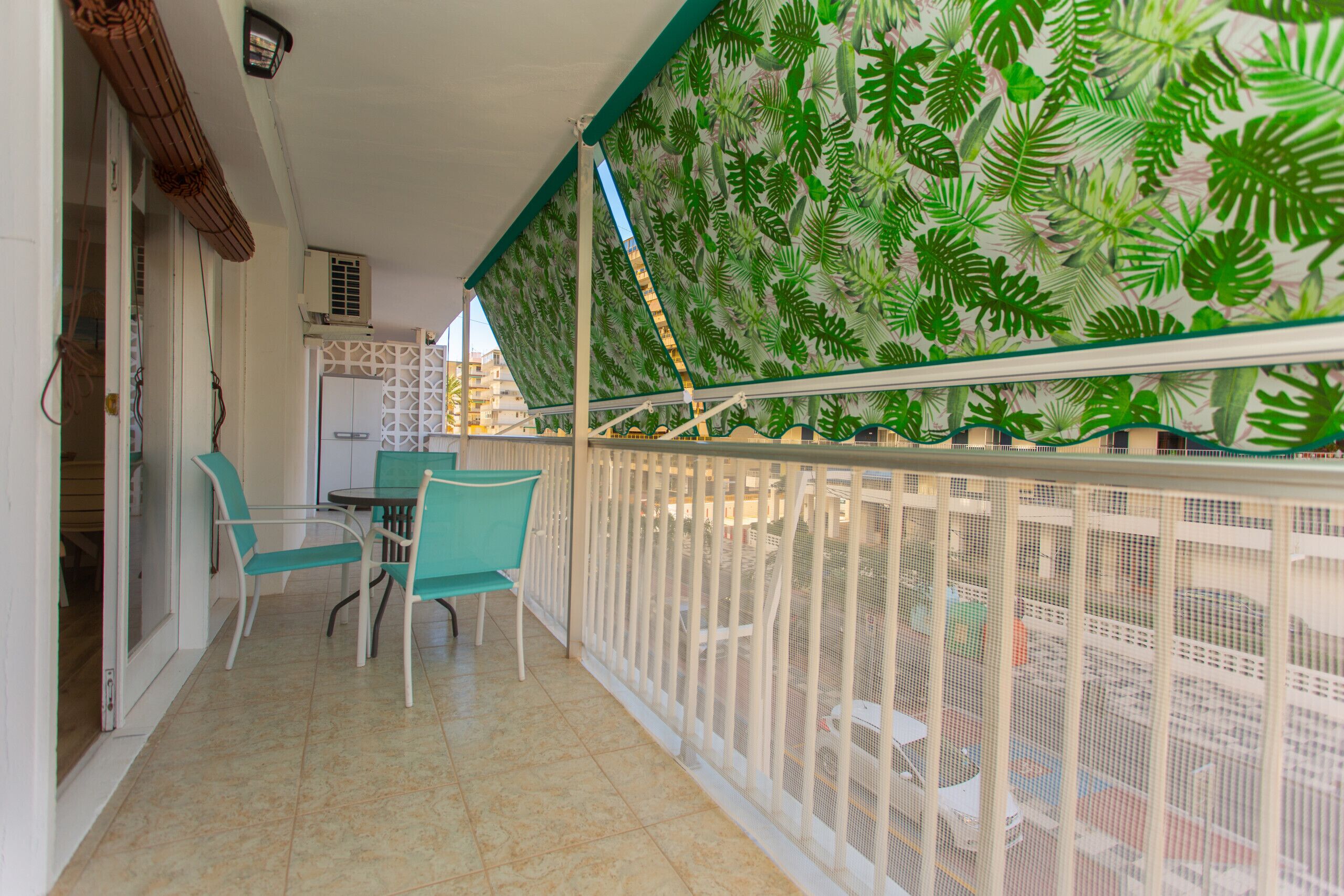 Ein Balkon mit weißer Brüstung, einem Tisch und zwei Stühlen.