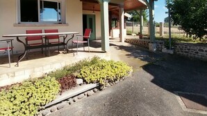 Ein Gebäude mit einer überdachten Terrasse, Sitzgelegenheiten im Freien und einer Steinmauer.