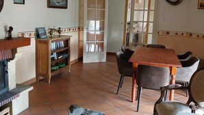 Ein Essbereich mit Holztisch und -stühlen, einer Kandelaberleuchte und einem Bücherregal mit Büchern.