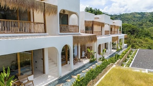 Un resort a più piani con posti a sedere all'aperto, una piscina e vista sulle colline circostanti.