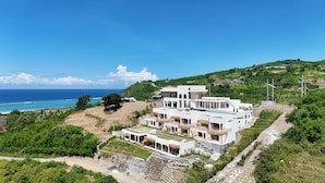 Una proprietà costiera con un grande edificio bianco, diversi balconi e vista sull'oceano.