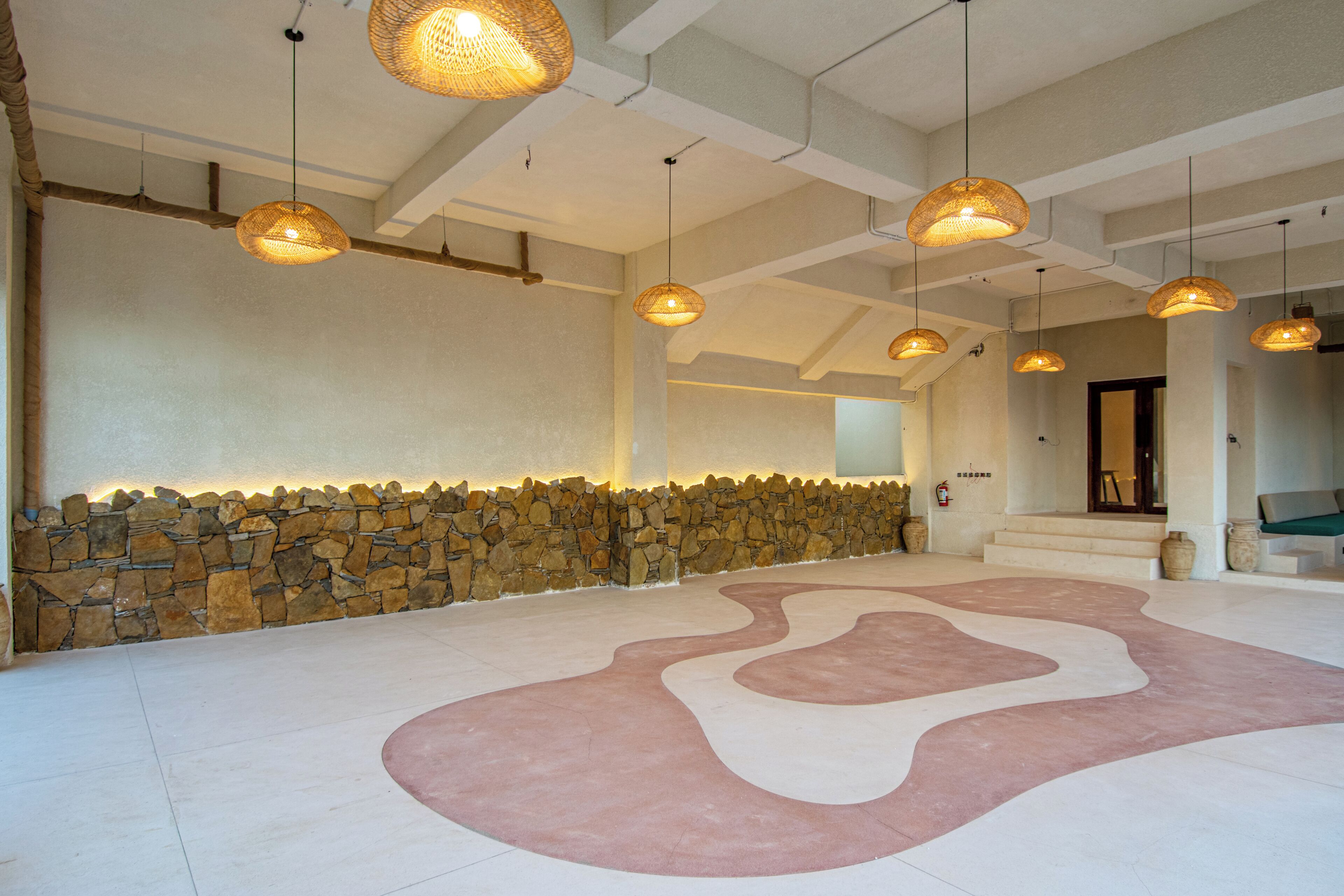A spacious lobby with a stone wall, a patterned floor, and multiple hanging lights.