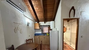 A compact kitchen with a dining area, wooden ceiling, and patterned floor tiles.