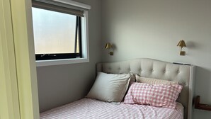 A bedroom with a bed, a window, and two wall-mounted lamps.