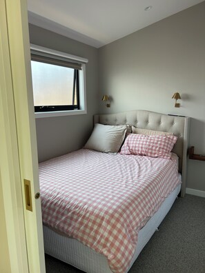 Een slaapkamer met een bed, een raam en twee wandlampen.