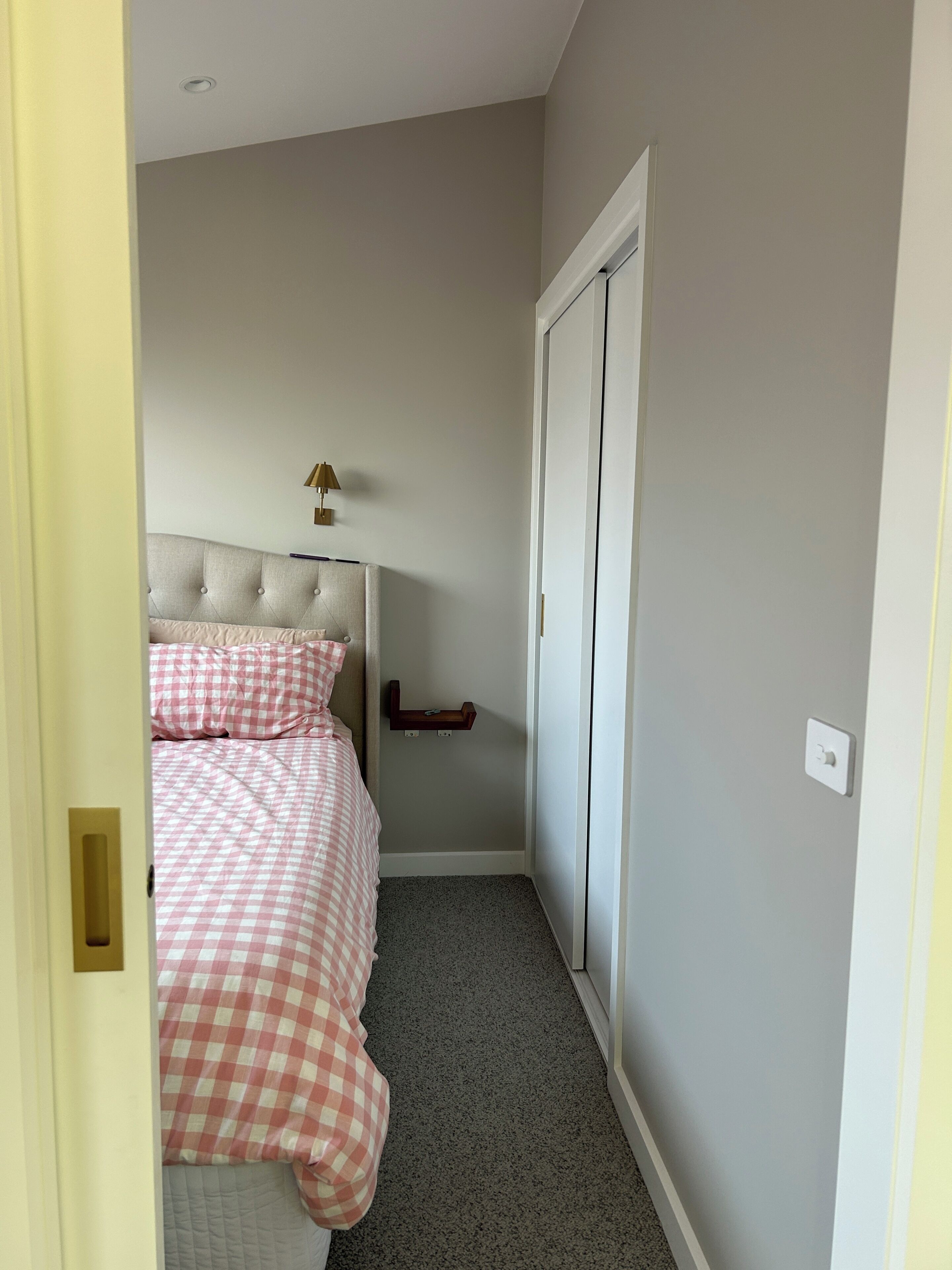A bedroom with a bed, a nightstand, a lamp, and a wardrobe.