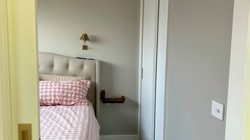 A bedroom with a bed, a nightstand, a lamp, and a wardrobe.