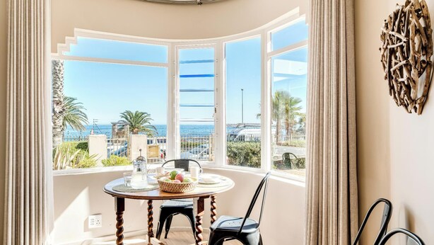 Una habitación con una mesa redonda, dos sillas, vistas al mar y un adorno en la pared.