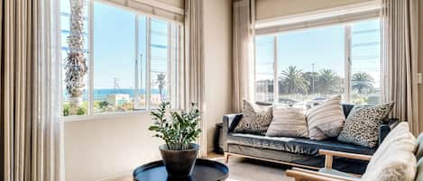 A modern living room with a sofa, armchairs, a coffee table, and a potted plant.