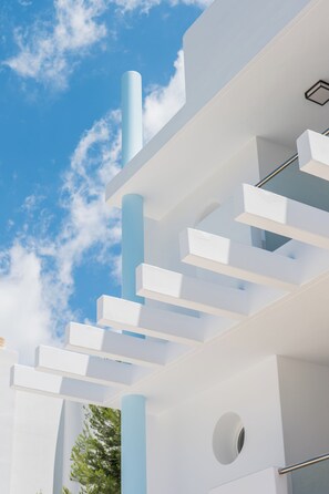 A modern architectural structure with white and light blue elements, a circular window, and a clear sky.