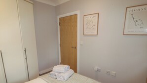 A bedroom with a bed, a wooden door, and two framed artworks on the wall. - Cornstore Cottage (Pembroke)