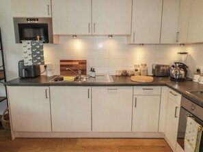 Uma cozinha moderna com forno embutido, pia e diversos eletrodomésticos.