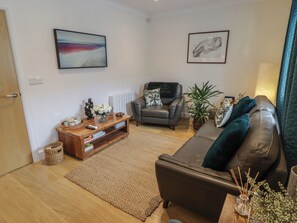 A living room with a sofa, a coffee table, a fireplace, and a painting on the wall.