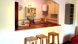 Una cocina con isla integrada, un reloj y un armario con un electrodoméstico blanco.