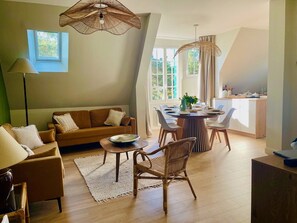 Ein modernes Wohnzimmer mit Sofa, Esstisch, Stühlen und einer Küchenzeile.