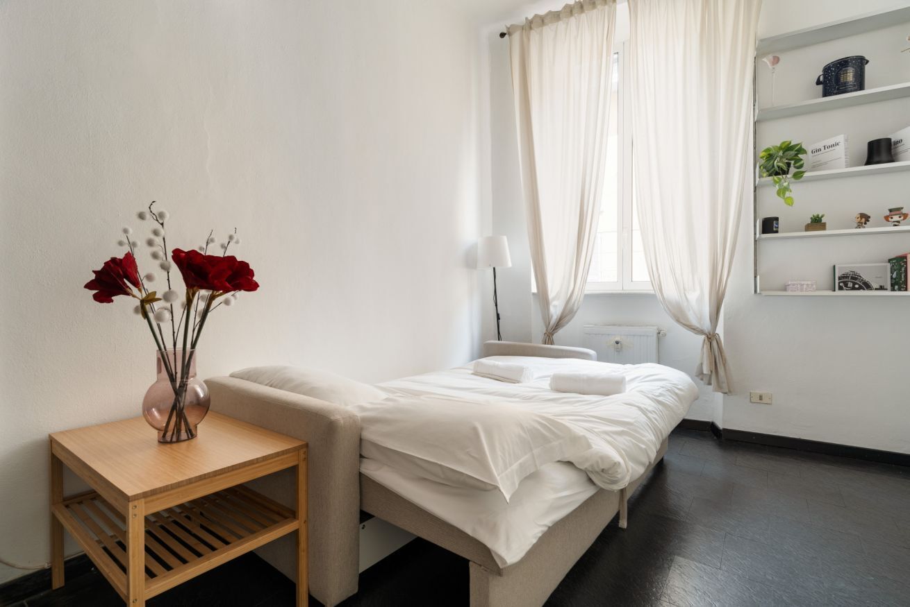 Ein Schlafzimmer mit Bett, Nachttisch und einem fenster mit Vorhängen.