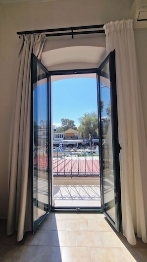Une pièce dotée d’une porte-fenêtre coulissante donnant sur un espace extérieur avec un sol carrelé et une clôture en métal.
