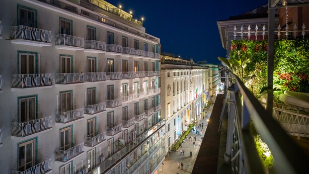 A multi-story hotel with balconies, a ground-floor restaurant, and a view of the street. - Toledo Rooftop | Panoramic Terrace | Grandi Residenze Napoli (Napoli)