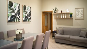 A dining area with a table and chairs, a sofa, and wall art. - Toledo Rooftop | Panoramic Terrace | Grandi Residenze Napoli (Napoli)