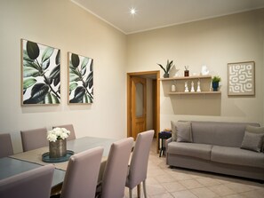 A dining area with a table and chairs, a sofa, and wall art. - Toledo Rooftop | Panoramic Terrace | Grandi Residenze Napoli (Napoli)