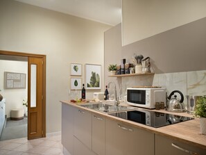 A modern kitchen with a microwave, sink, and wooden countertop. - Toledo Rooftop | Panoramic Terrace | Grandi Residenze Napoli (Napoli)