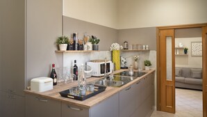 A modern kitchen with a central island, built-in appliances, and a wooden door leading to a living area. - Toledo Rooftop | Panoramic Terrace | Grandi Residenze Napoli (Napoli)