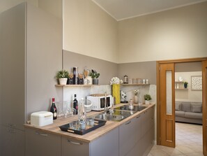 Una cocina moderna con una isla central, electrodomésticos integrados y una puerta de madera que da a una sala de estar.