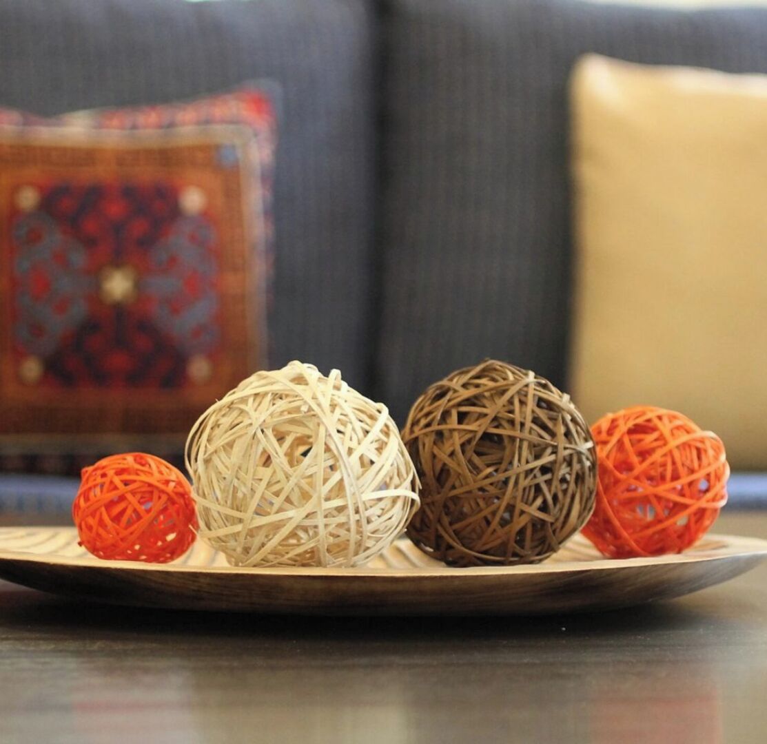 A plate with four woven balls of different colors.