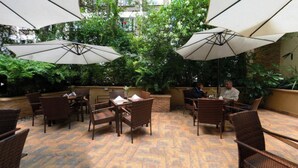 An outdoor patio area with wicker furniture, umbrellas, and greenery. - Reata Apartment Hotel (Nairobi)