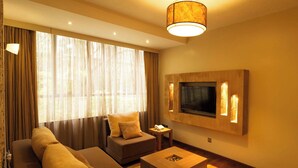 A modern hotel room with a sofa, armchair, TV, and a small table. - Reata Apartment Hotel (Nairobi)