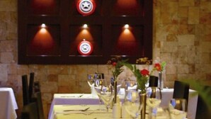 A restaurant with a long table set for dining, a wall with illuminated signs, and a stone wall in the background. - Reata Apartment Hotel (Nairobi)