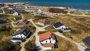 Oversigtsbillede af en kystlandsby med huse, et fyrtårn og en strand.