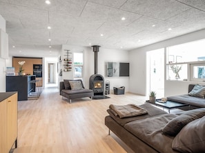 Ein modernes Wohnzimmer mit Kamin, Sofa und einer Küche im Hintergrund.