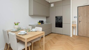 Una cocina moderna con comedor, horno empotrado y una pequeña mesita auxiliar.