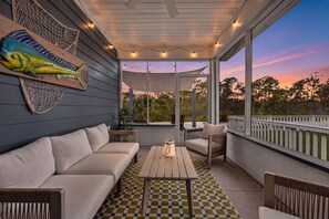 A covered outdoor seating area with a checkered floor, a wooden table, and a fish wall art piece.